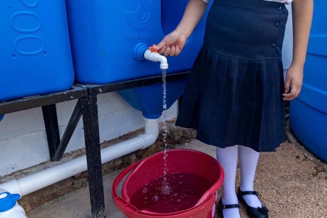 Niña llenando una cubeta de agua