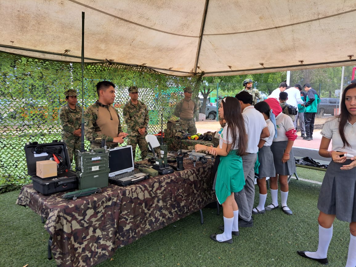 militares detrás de mesa en exposición con estudiantes