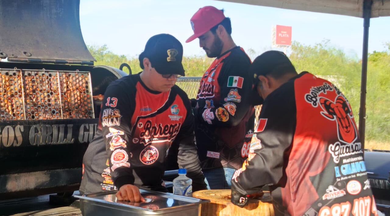 Tres personas preparando carne junto a un asador