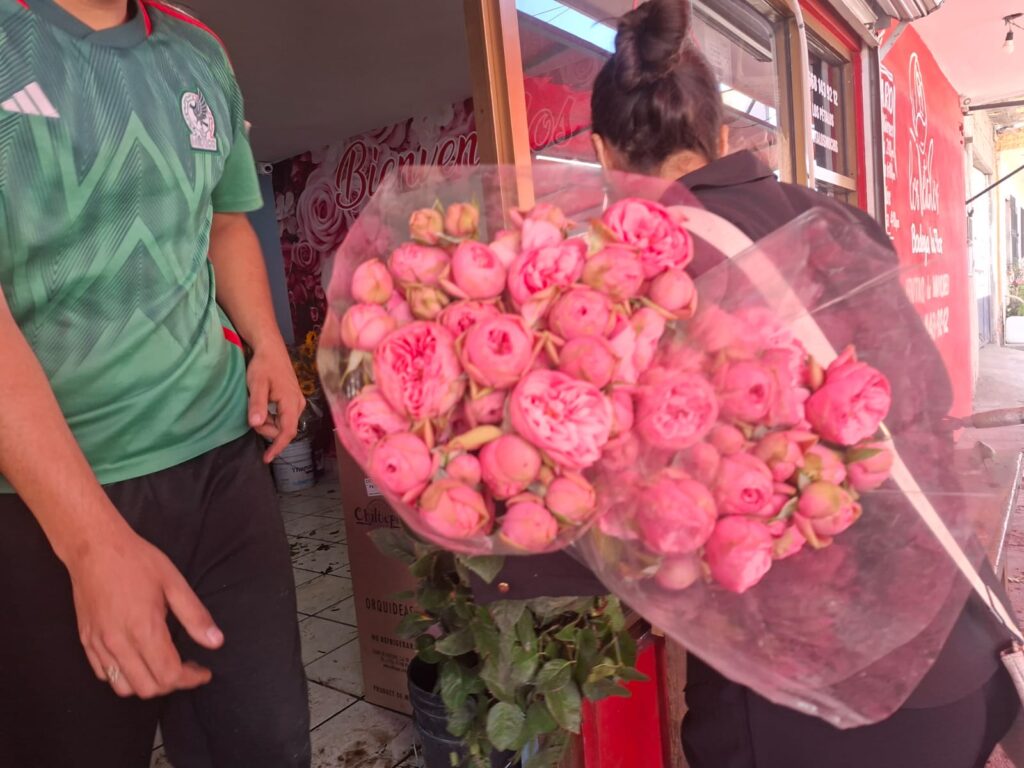 Ramo de flores rosas junto a dos personas