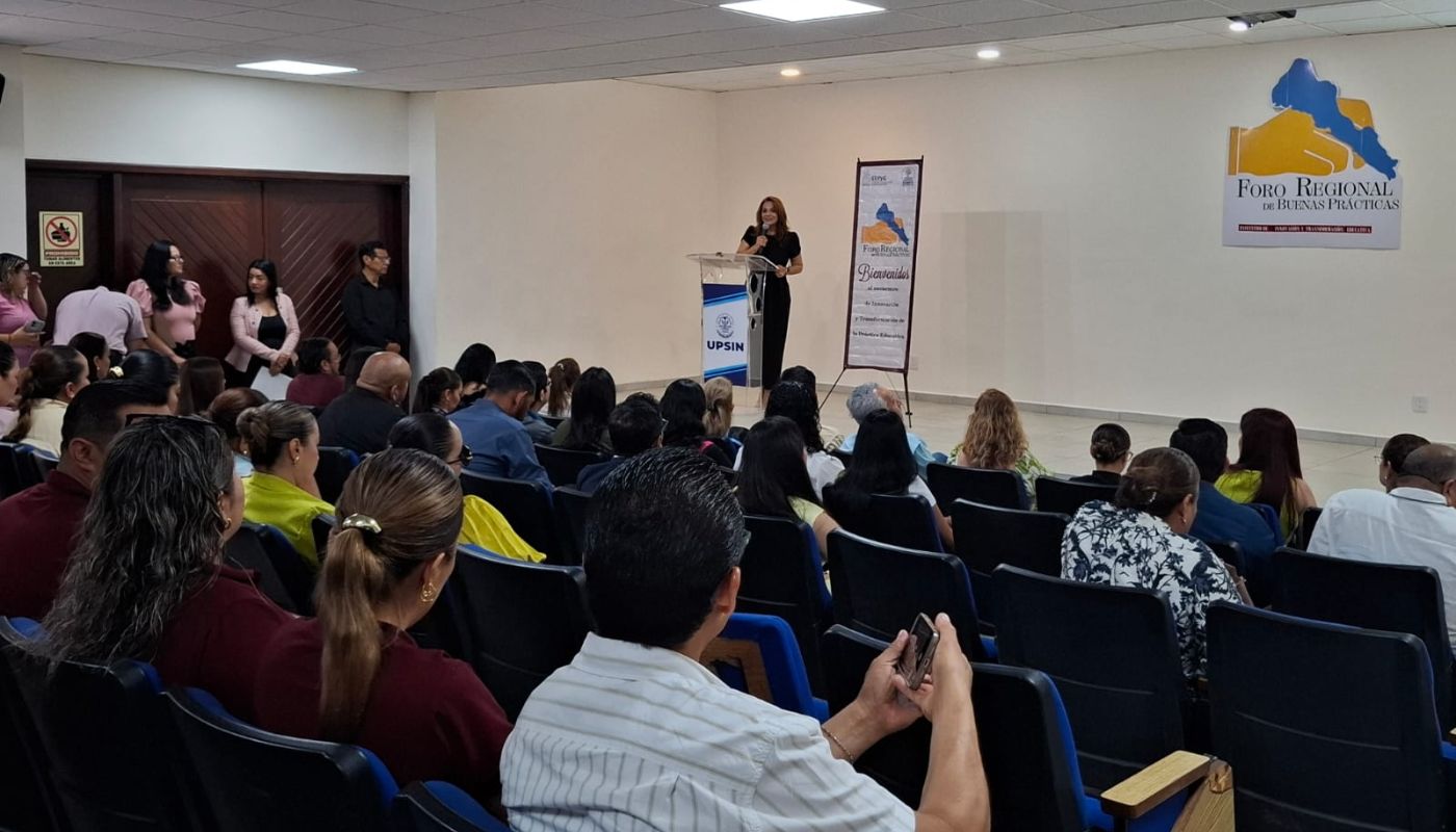 Maestros dentro de un auditorio presenciando una conferencia