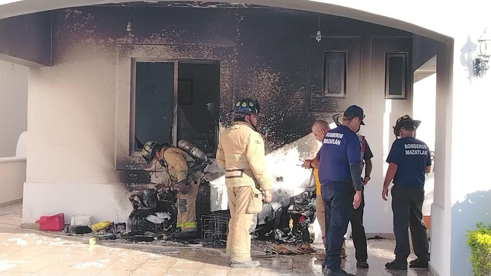 Casa con manchas negras del fuego junto a elementos de los bomberos