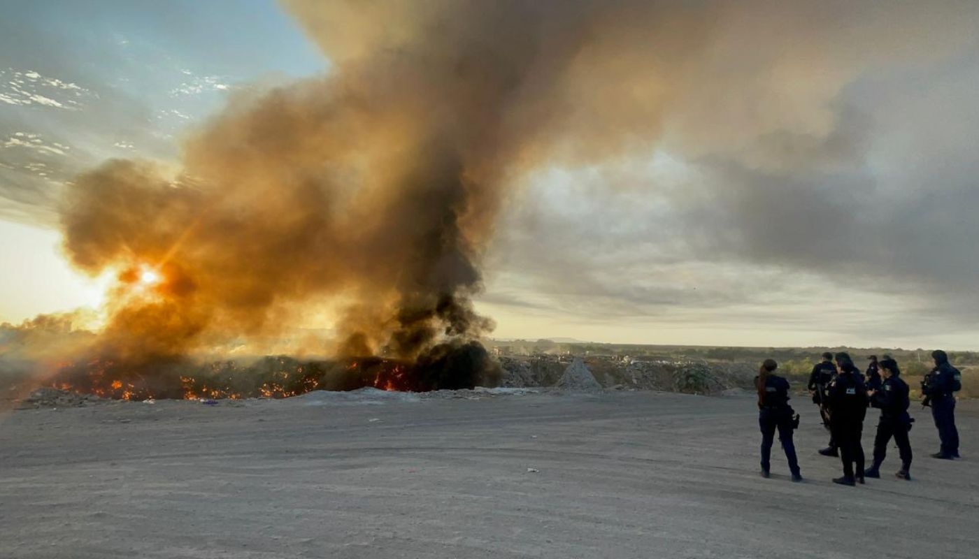 Agentes policiacos frente a un incendio en una zona de basurero