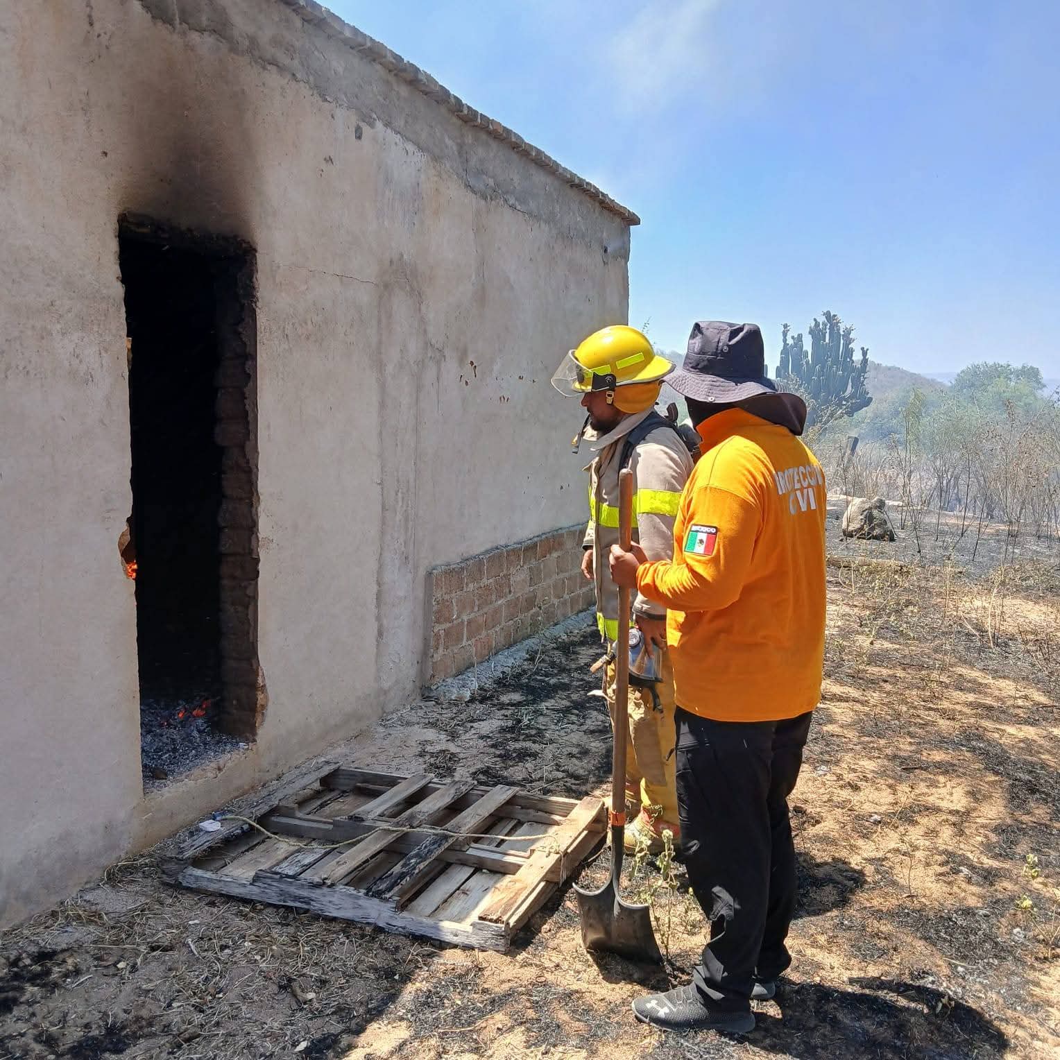 Dos bomberos en la puerta con marca de fuego en color negro