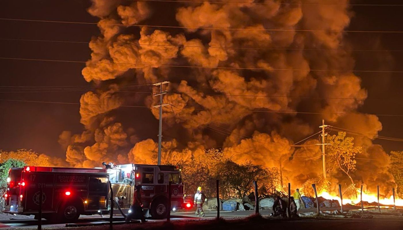 Unidad de bomberos en una calle frente a una explosión y nube de humo por un incendio