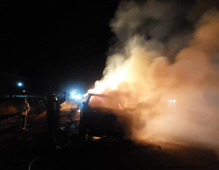 Camioneta incendiada con humo y bombero apagando el fuego