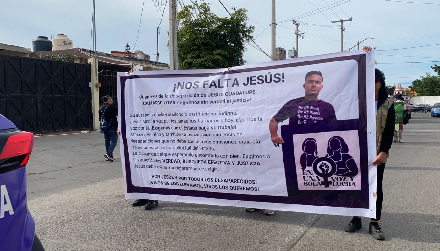 personas en una calle sosteniendo una lona