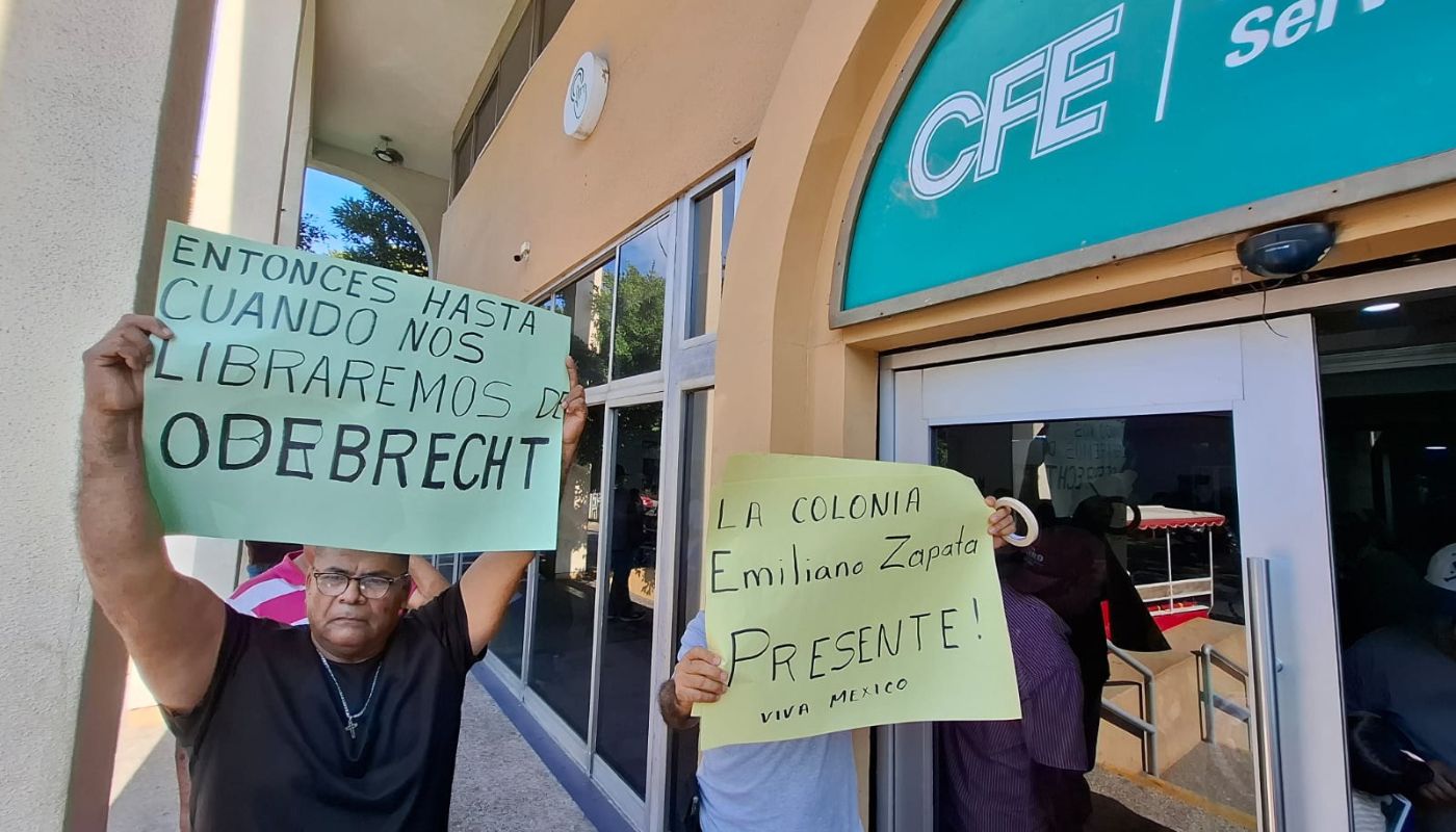 Personas con pancartas en una manifestación afuera de unas oficinas de CFE