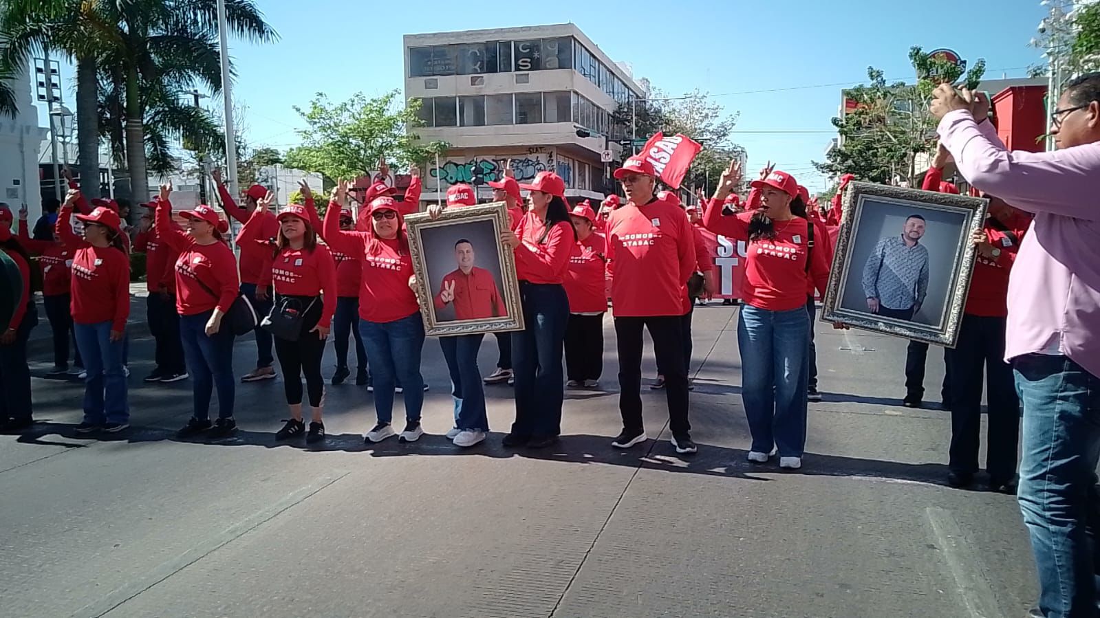 Personas vestidas de rojo marchando por la calle con fotos