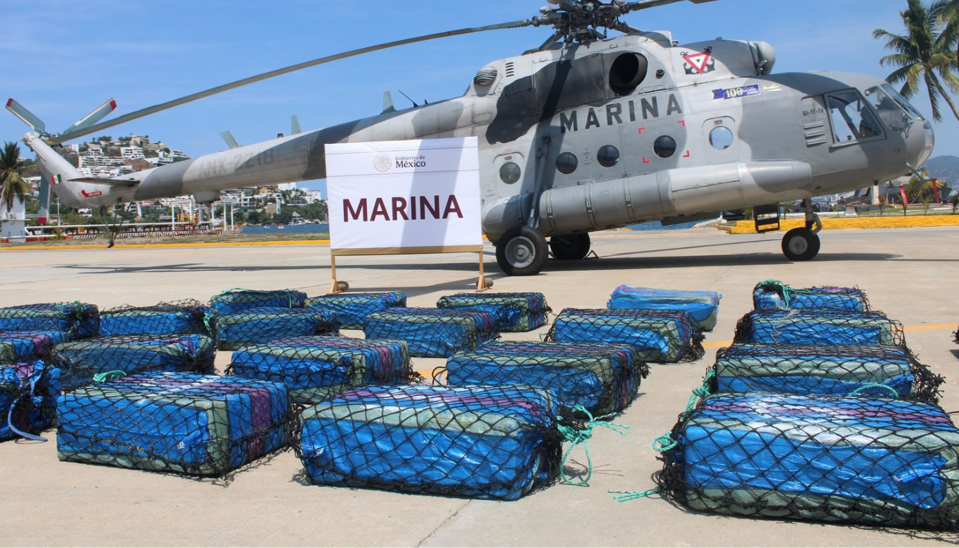 Un helicoptero de la marina gris al fondo con bultos azules enfrente