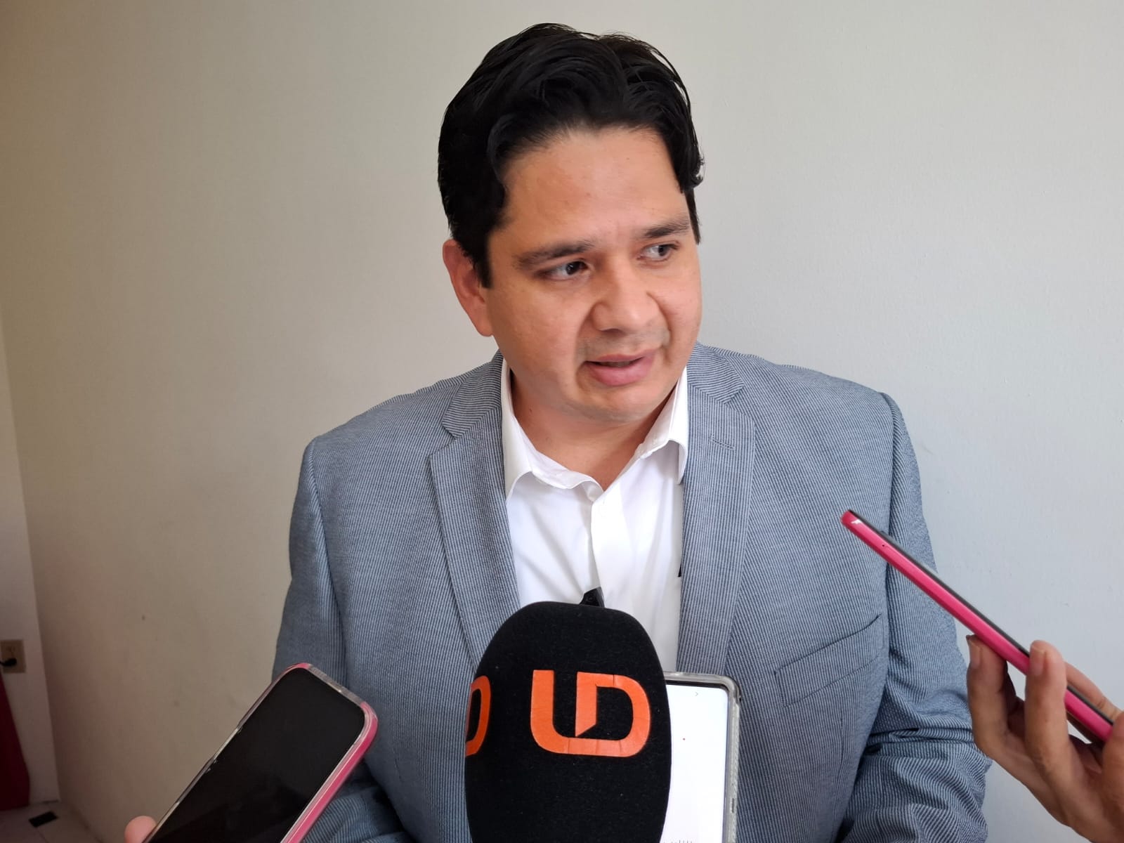 Hombre hablando a micrófono y grabadoras de teléfono