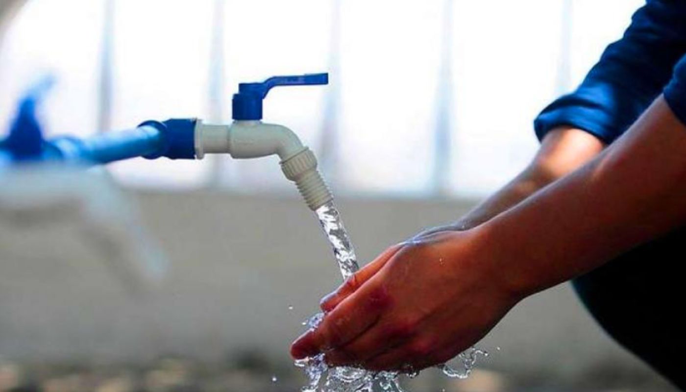Manos de una persona colocadas debajo de un grifo del que sale agua