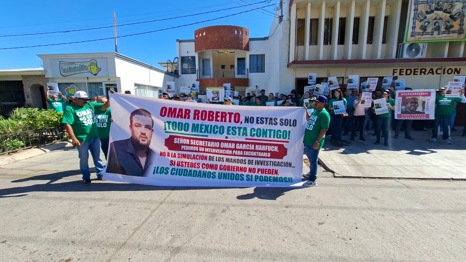 Personas realizando una manifestación con pancartas afuera de una institución