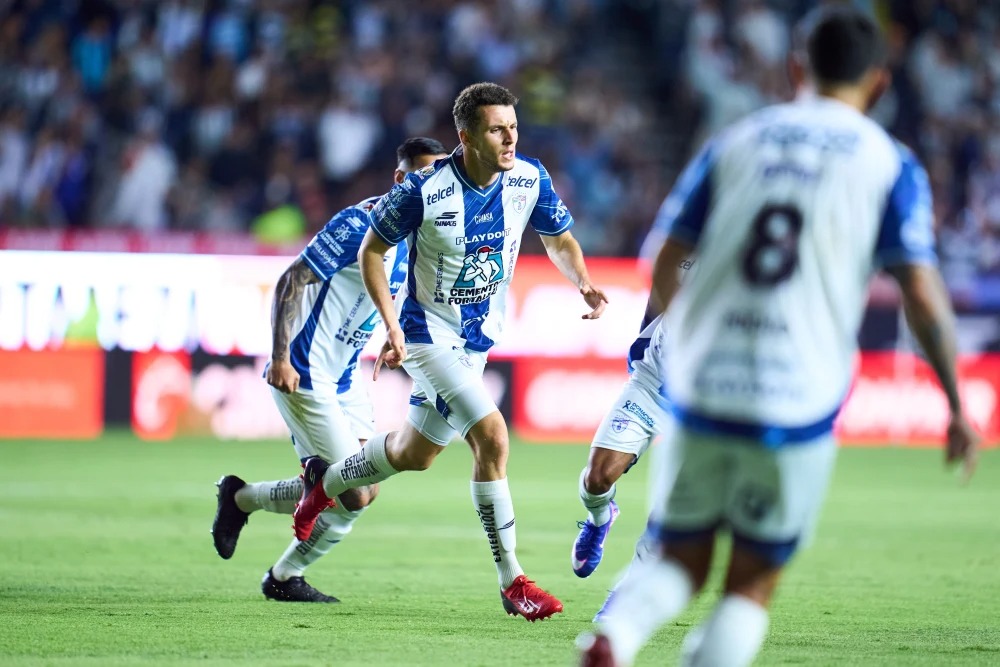 Idrissi gritando gon el uniforme del pachuca blanco y azul