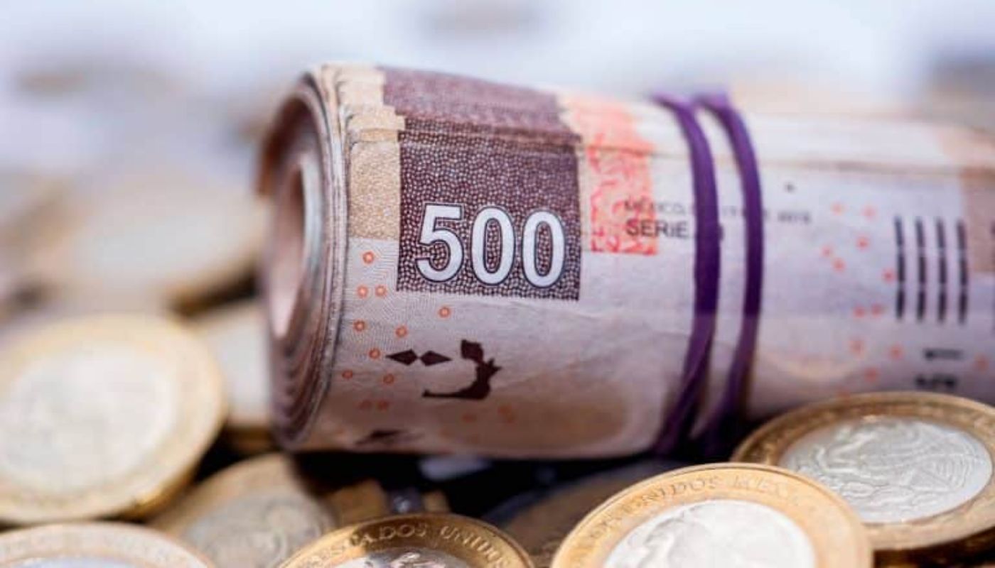 Rollo de billetes de quinientos pesos y monedas de diez pesos debajo
