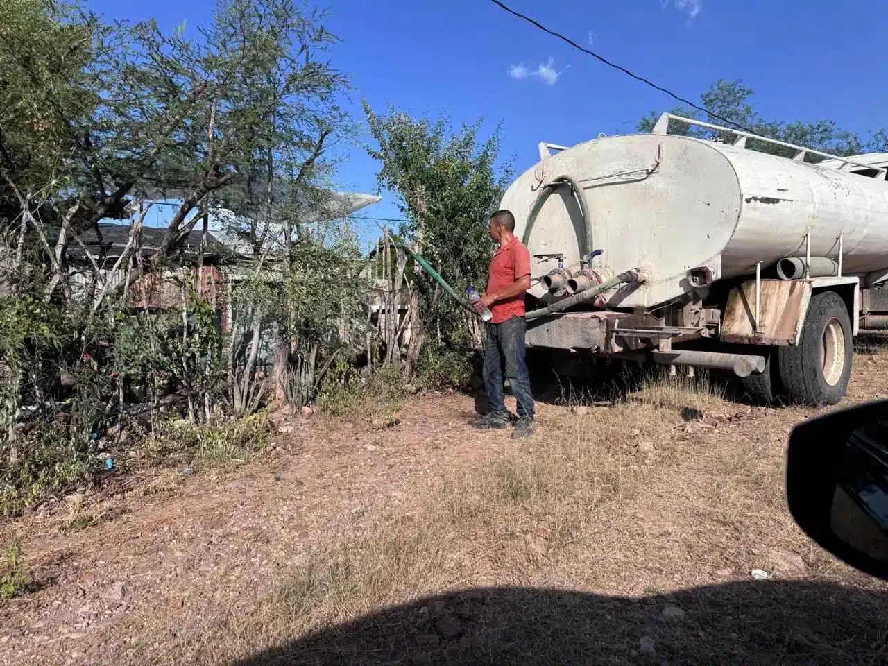 Un hombre junto a una pipa distribuidora de agua potable.