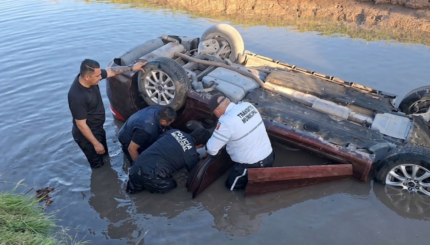 Agentes de Vialidad y Seguridad realizando rescate a un hombre atrapado dentro de un carro que cayó a un canal
