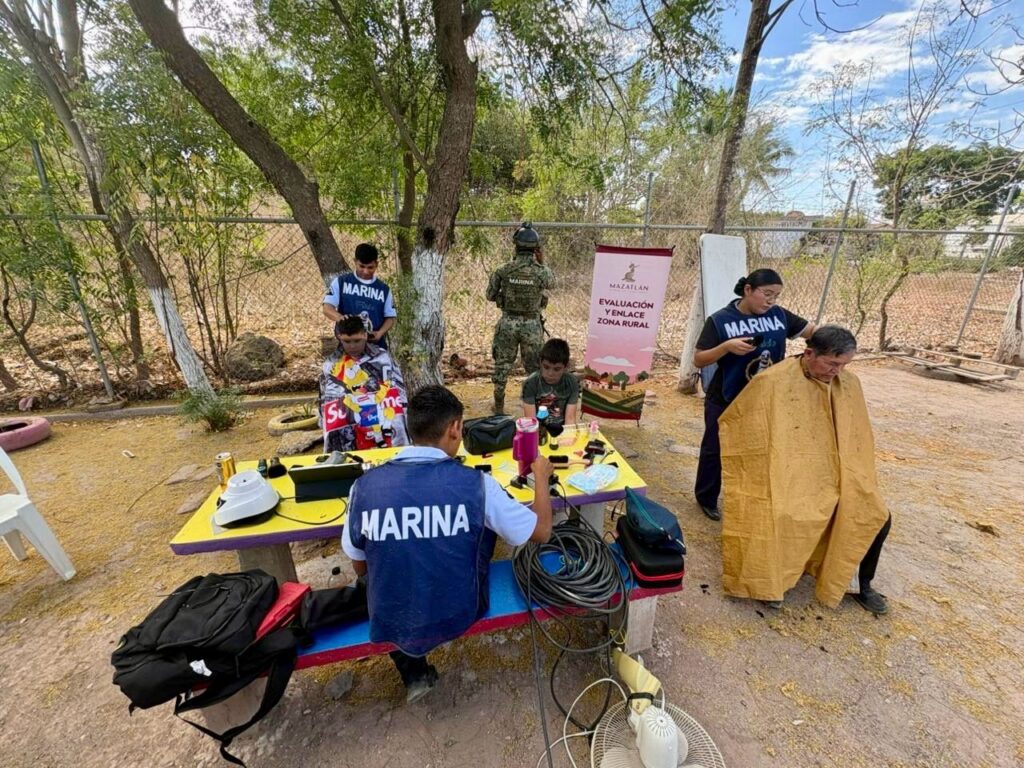Personal de la Marina laborando en una comunidad con bancas y mesas