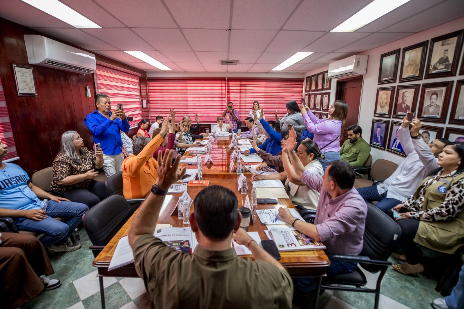 personas en sala de juntas levantando la mano