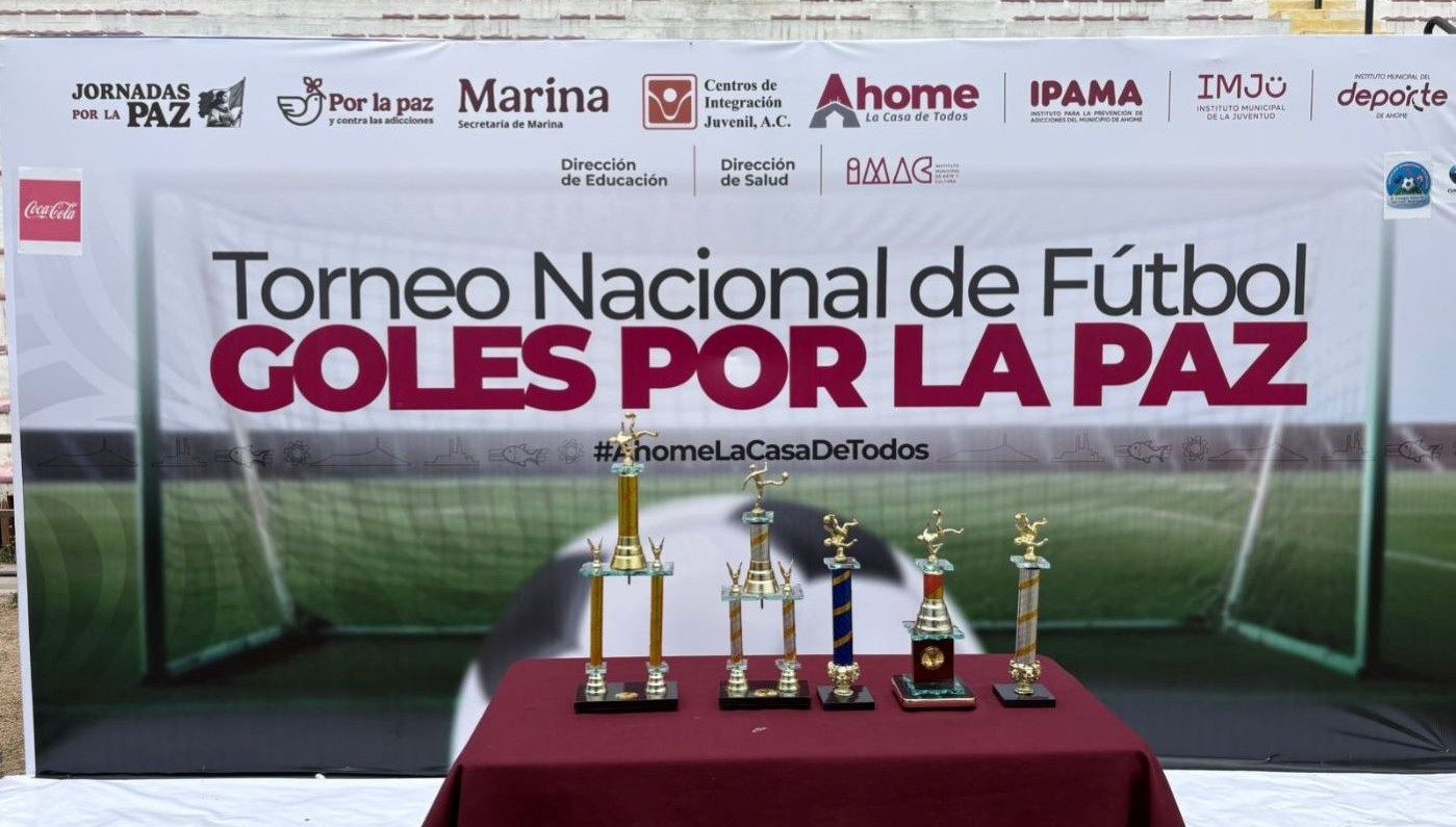 Mesa con trofeos y al fondo un banner de un evento