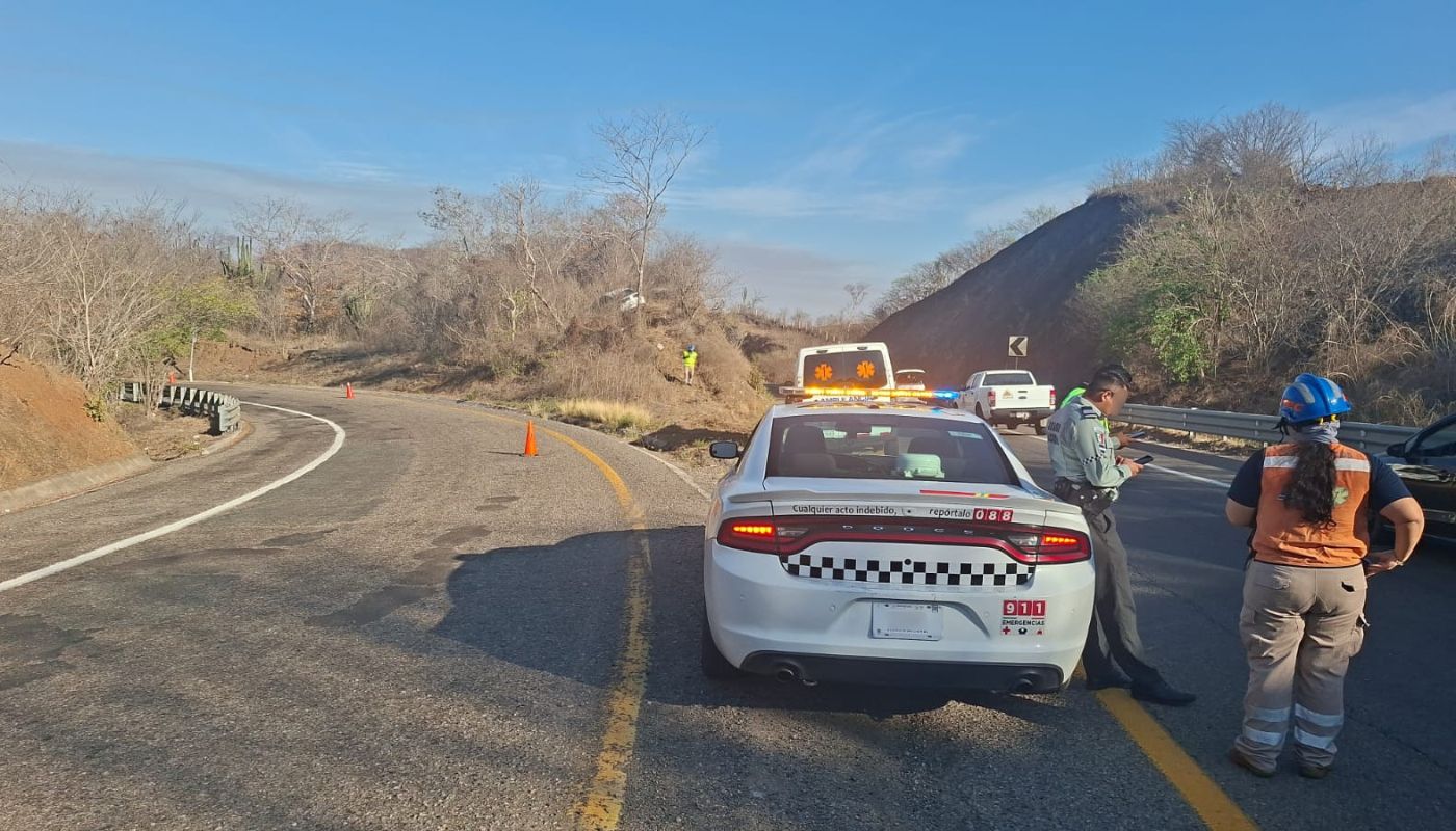unidades de cuerpos de emergencia y elementos en una carretera, al fondo un automovil de color blanco entre la maleza