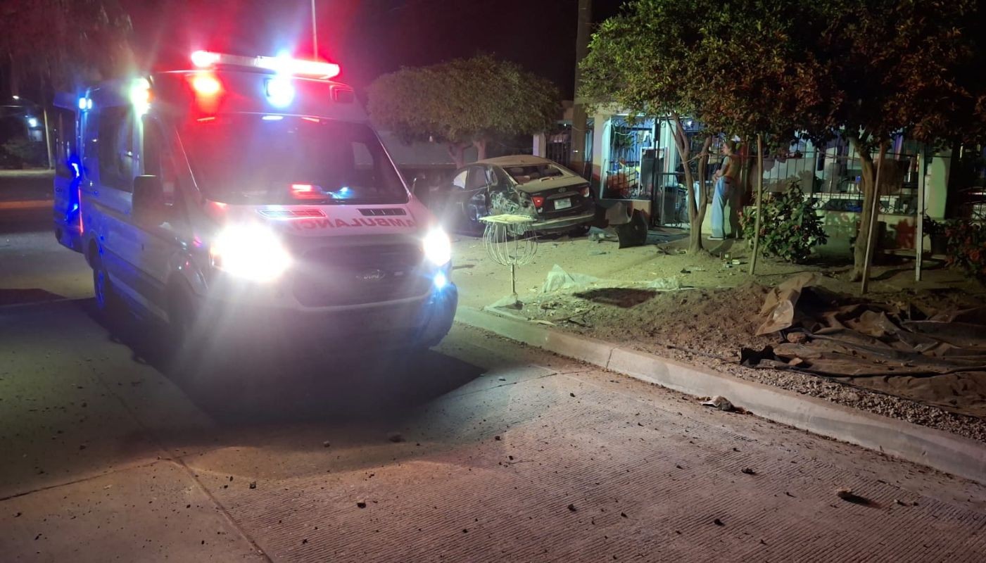 Unidad de la Cruz Roja afuera de una casa donde hay un carro color negro con golpes tras un accidente