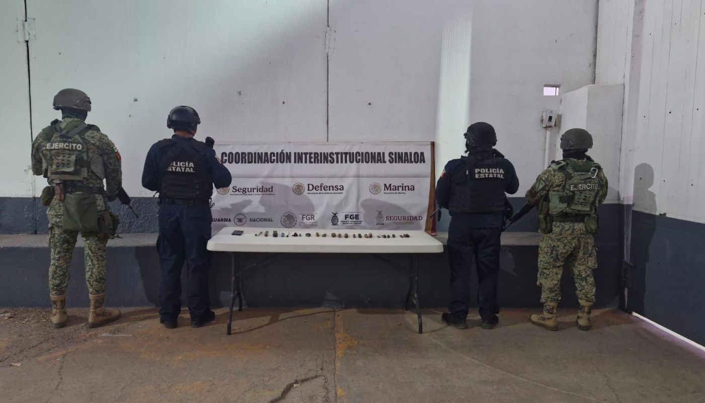 Elementos policiacos sosteniendo una nola y entre ellos una mesa con objetos