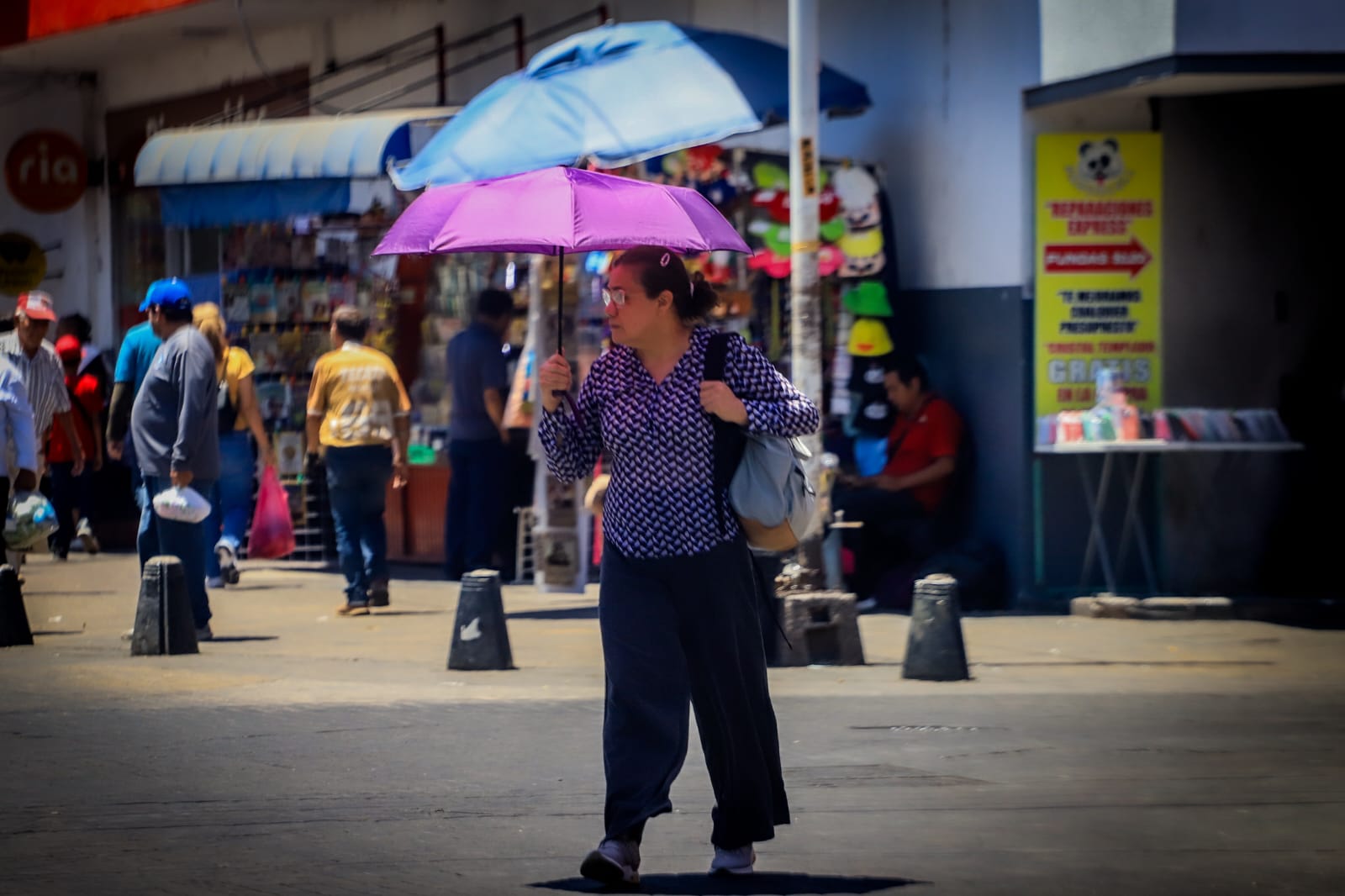 persona con una sombrilla caminando por una calle bajo el sol ardiente