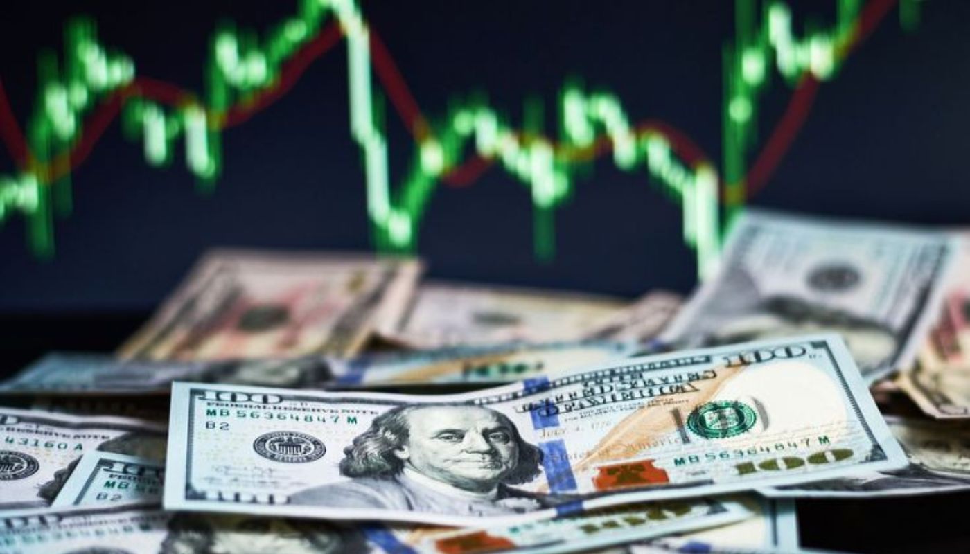 Billetes de dólar y al fondo una gráfica con variaciones
