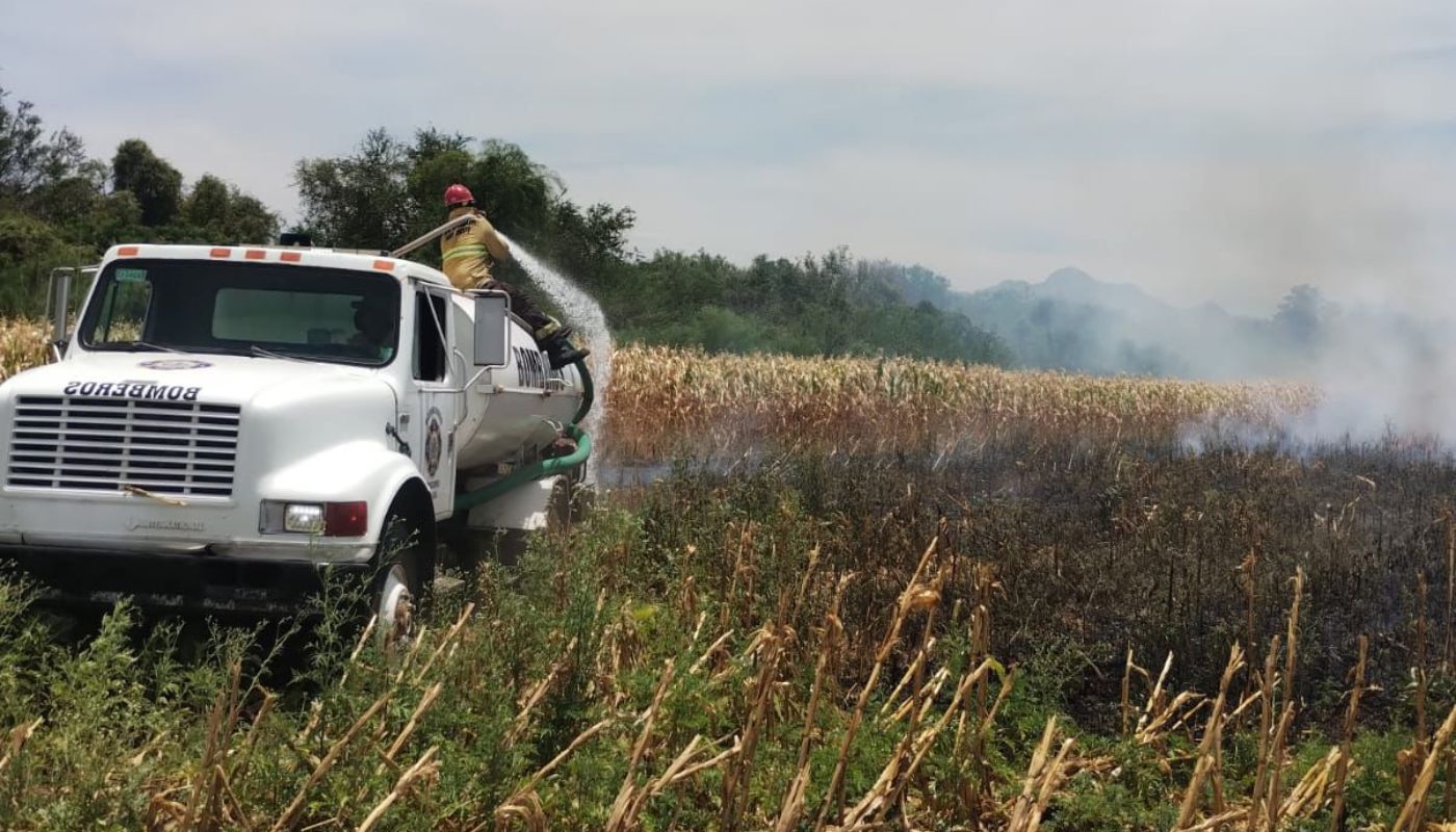 Campo incendiado siendo contenido por equipo de bomberos