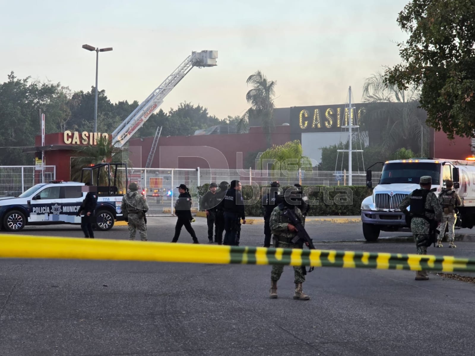 casino con humo por incendio y elementos policiacos desplegados en la zona con una cinta amarilla de precaución