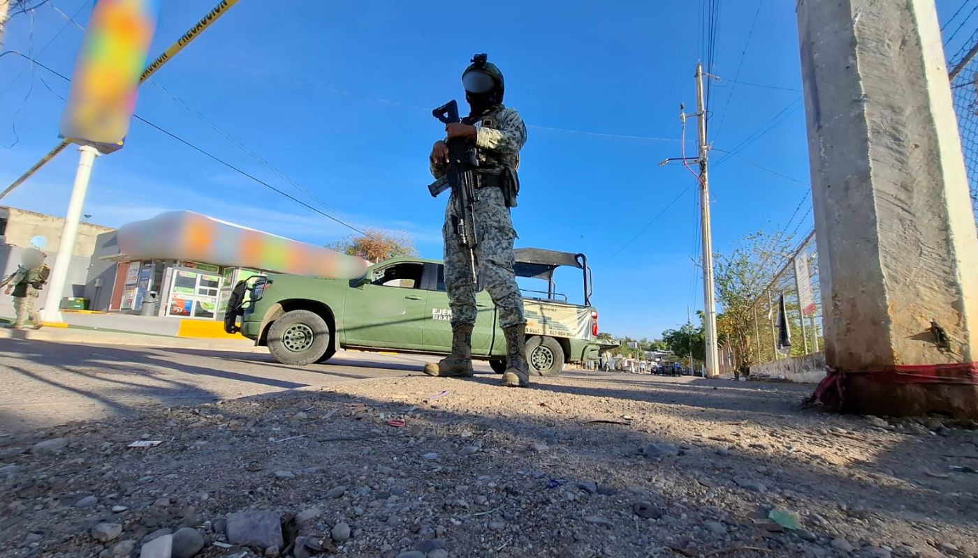 Elementos del Ejército Mexicano junto a una unidad de la corporación en una calle con una cinta amarilla de precaución