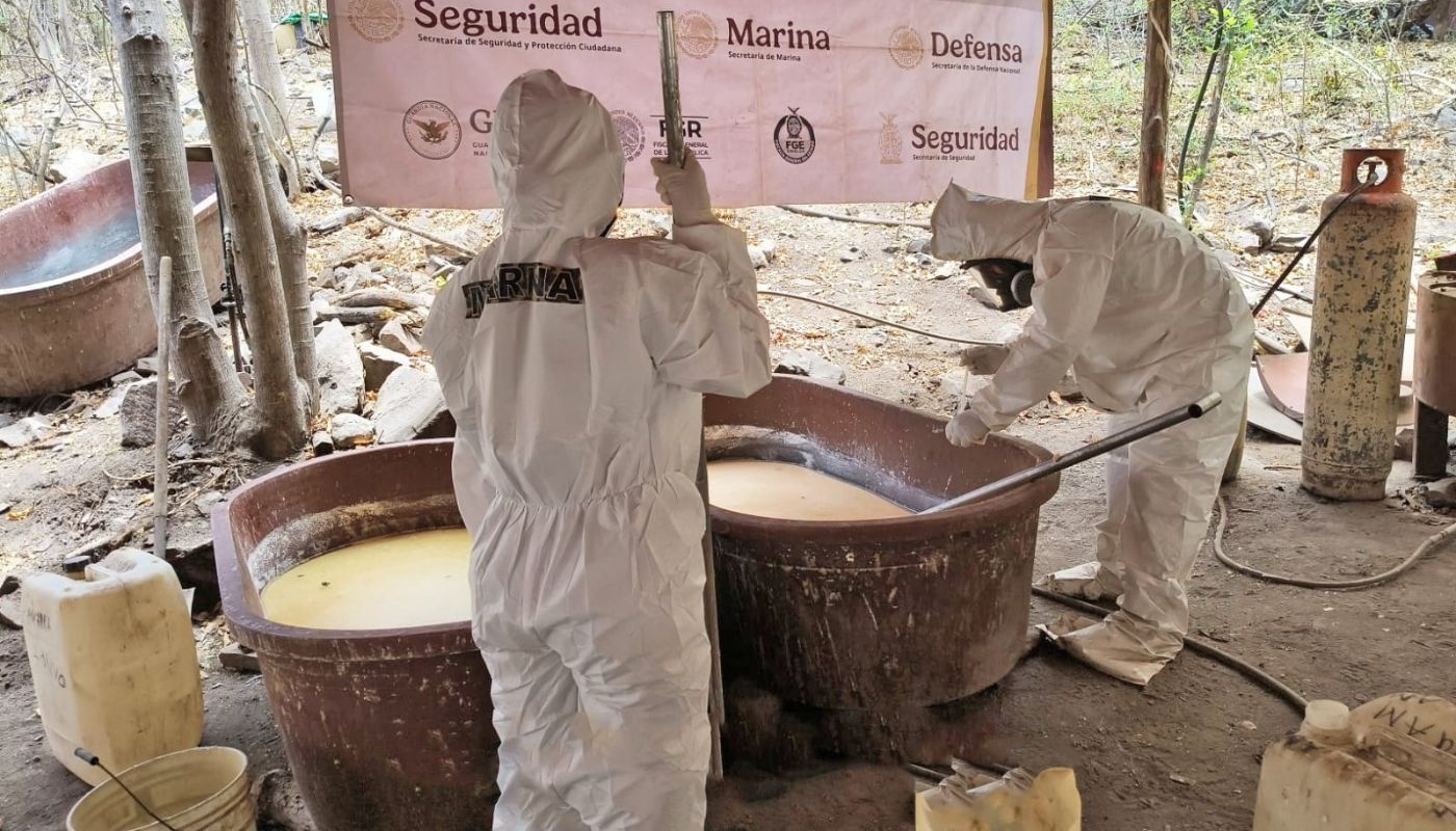 Personal especializado con trajes en un laboratorio clandestino con tinas con liquidos y otros objetos