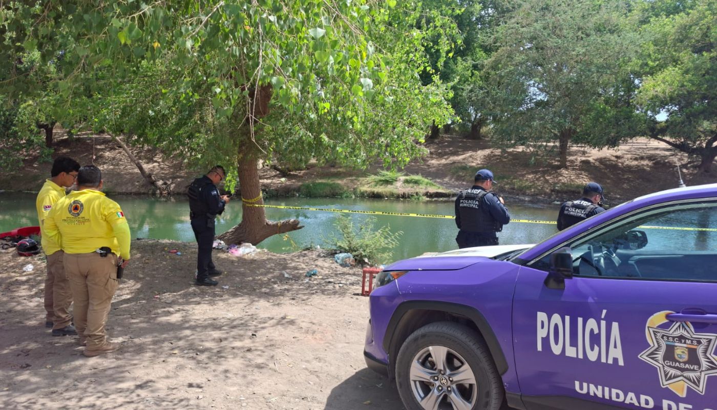Agentes policiacos cerca de un canal con una cinta amarilla de precaución delimitando el área