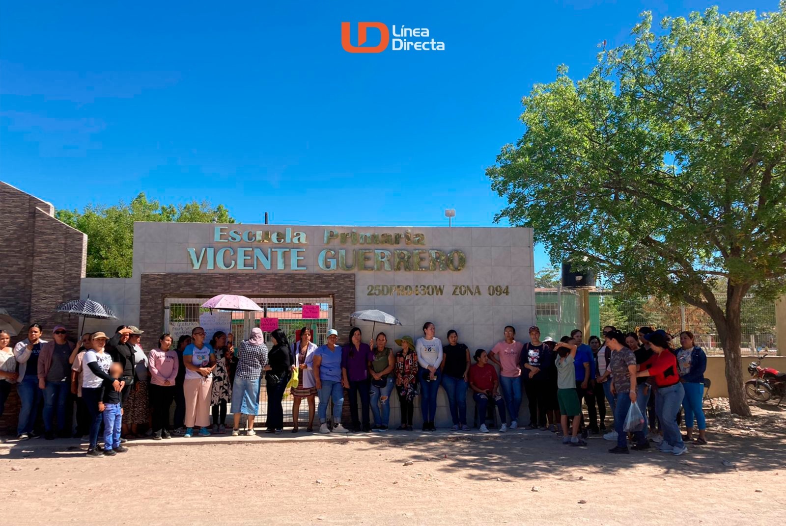 Personas, padres de familia, manifestandose afuera de un plantel educativo