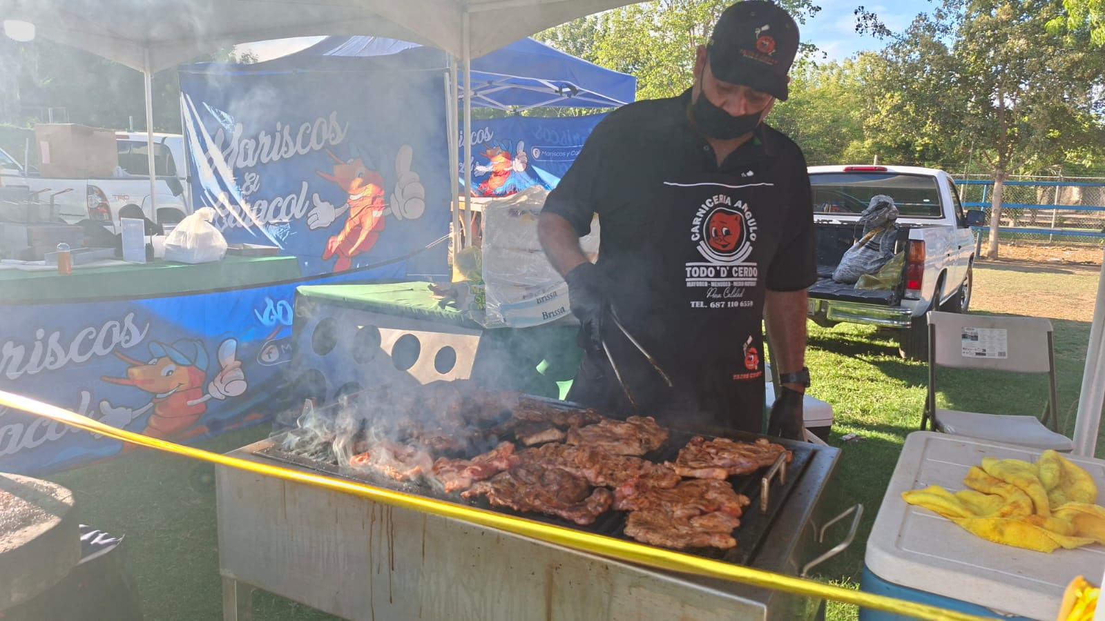 Persona asando carne con mucho humo blanco en la parrilla