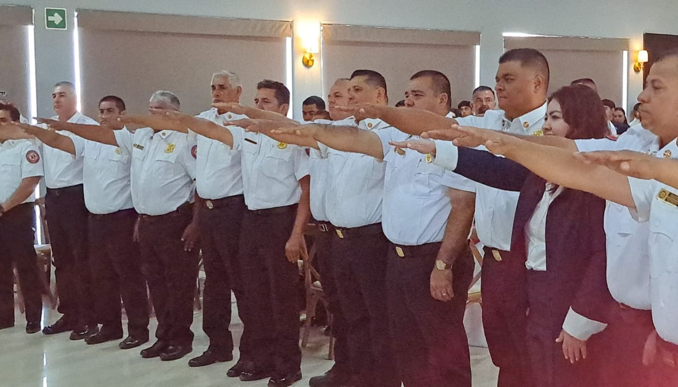 Personas levantando la mano en una toma de protesta en un salón de eventos