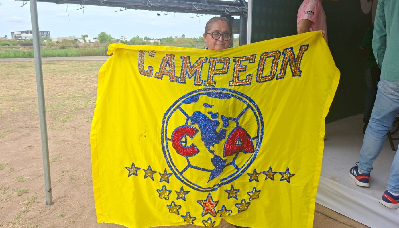 persona sosteniendo una bandera amarilla con el logo del Club Amércia