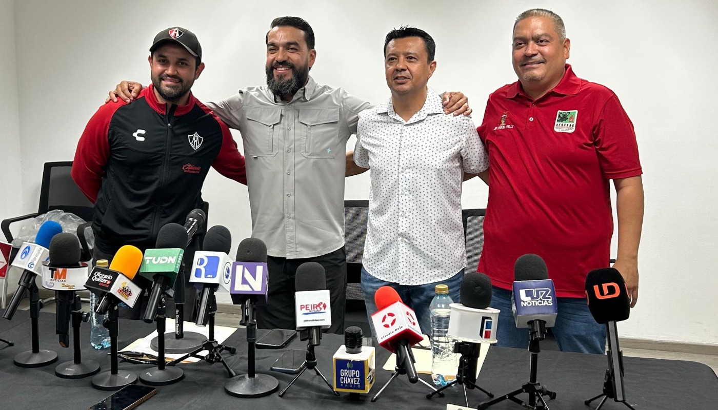 Personas de pie atrás de una mesa con micrófonos durante una rueda de prensa