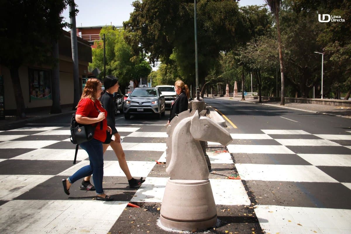 Personas cruzando calle pintada como tablero de ajedrez