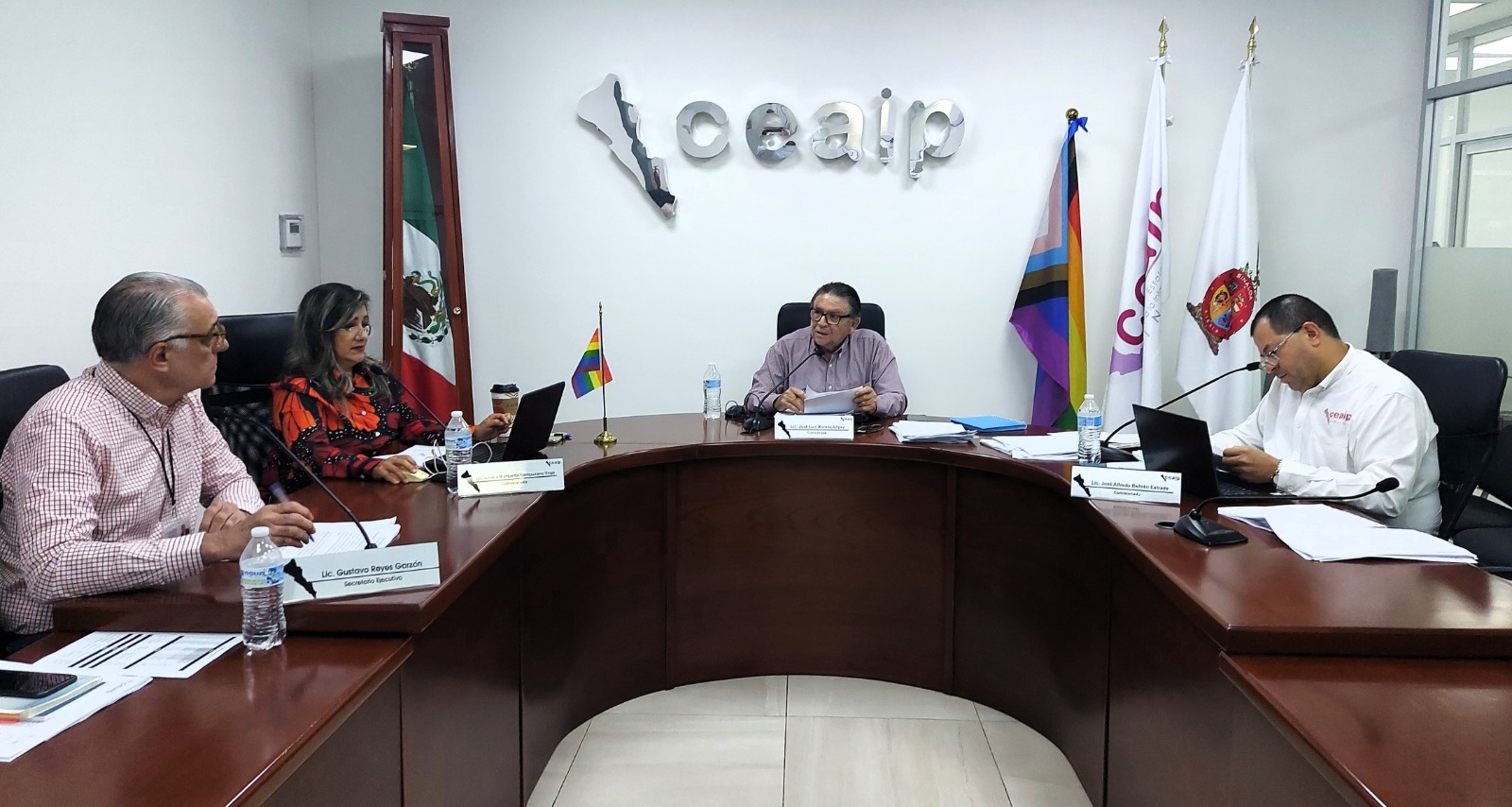 Personas en una reunión en una oficina con banderas de México