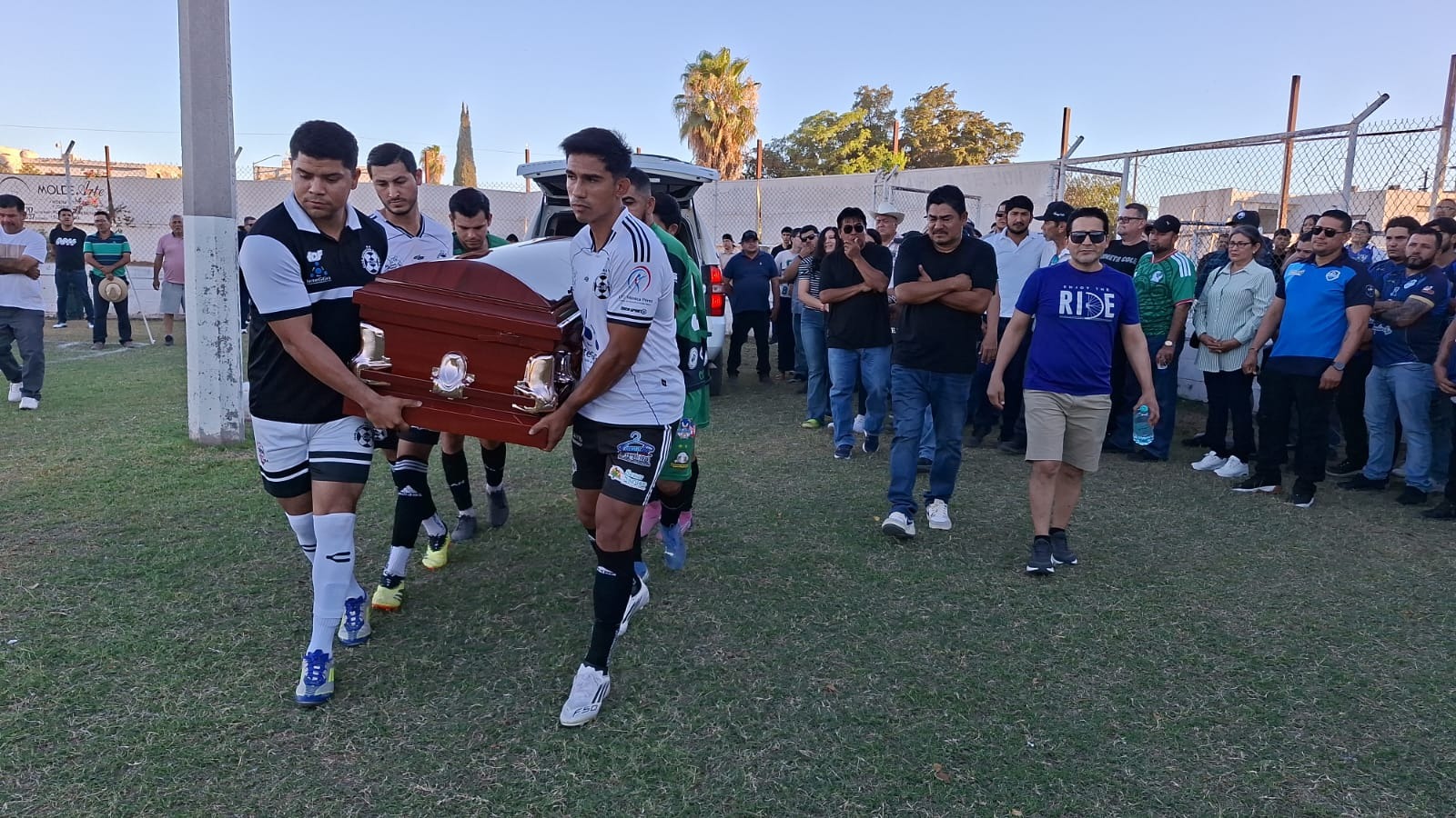 Personas cargando un ataúd en una cancha deportiva