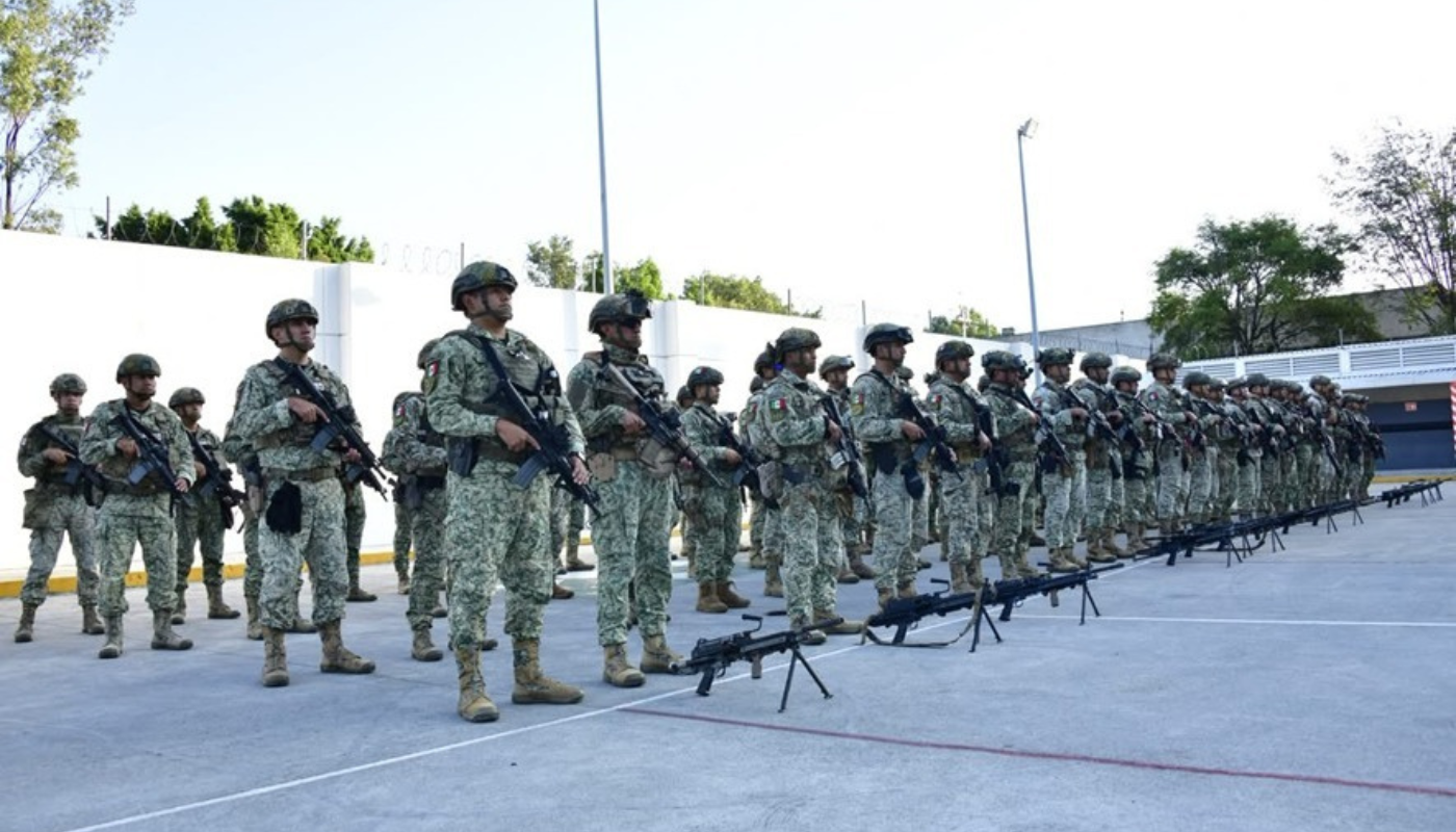 Elementos militares en formación con armas en el suelo