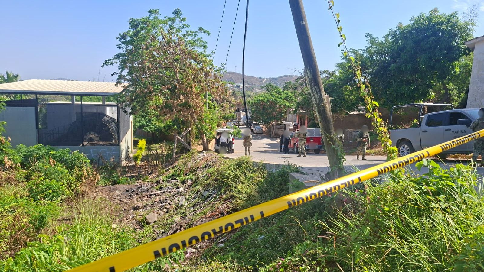 Cinta amarilla delimitando un área de terreno baldío y elementos y unidades del Ejército en una calle