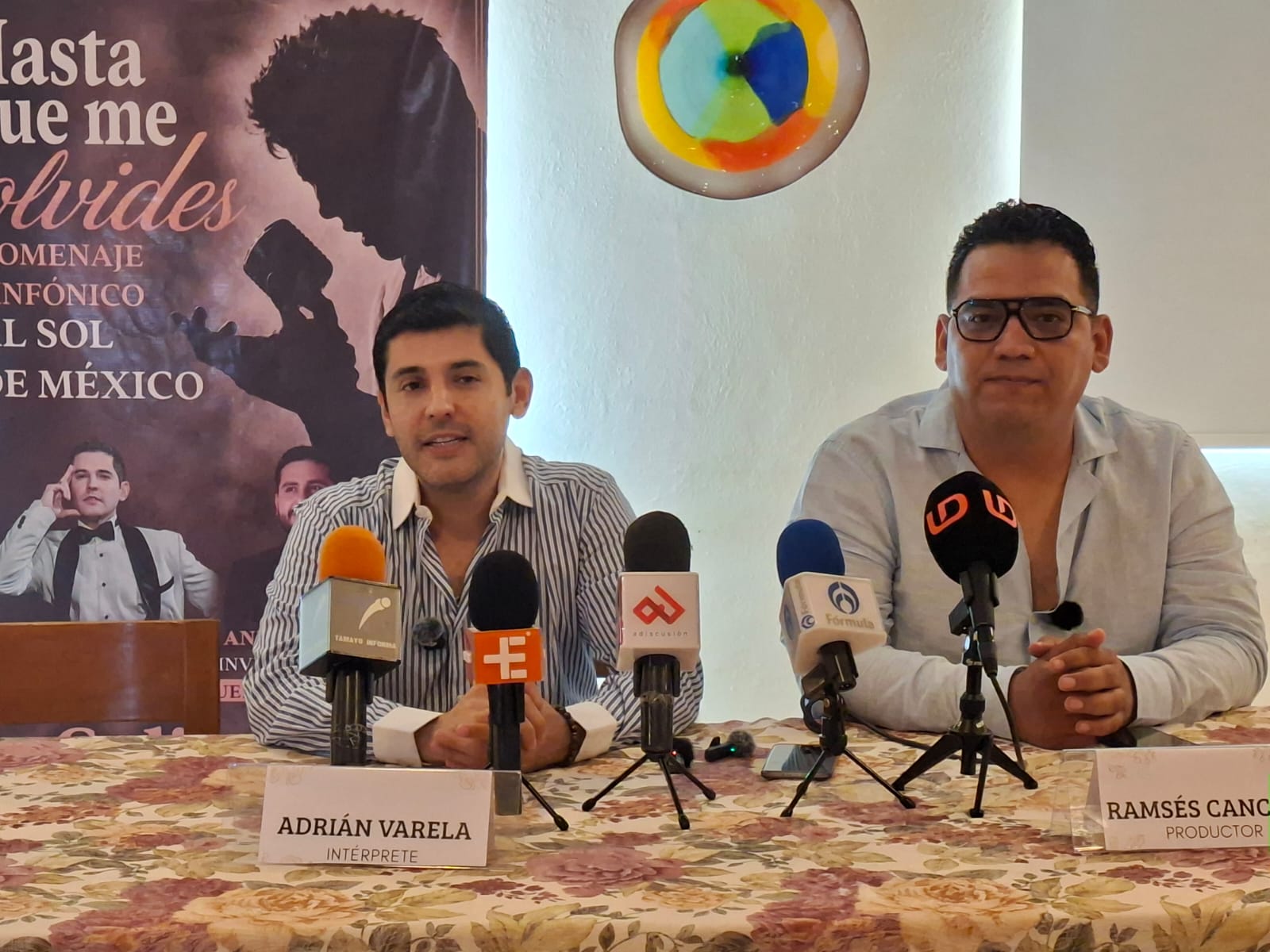 Personas en una rueda de prensa con micrófonos sobre una mesa