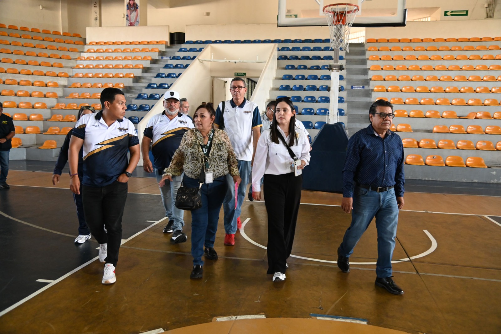 Personas caminando adentro de un gym/auditorio escolar