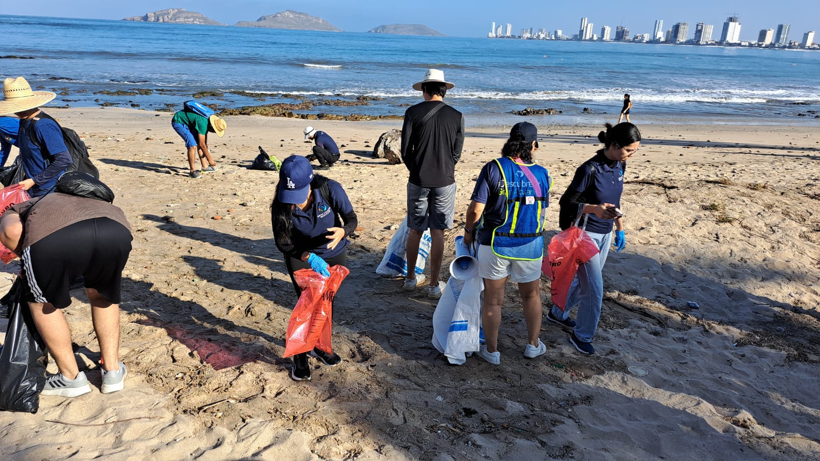 Personas con bolsas y costales en la arena del mar