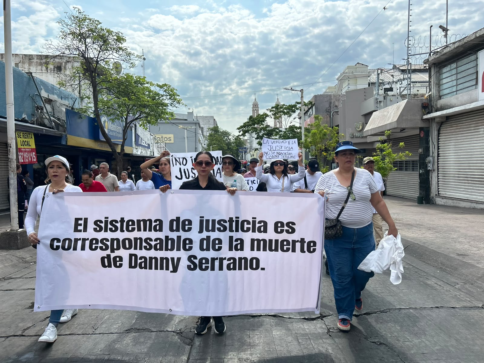 Personas marchando en una calle con pancartas
