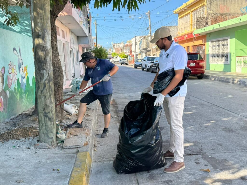 Dos personas con una escoba y una bolsa de la basura negra