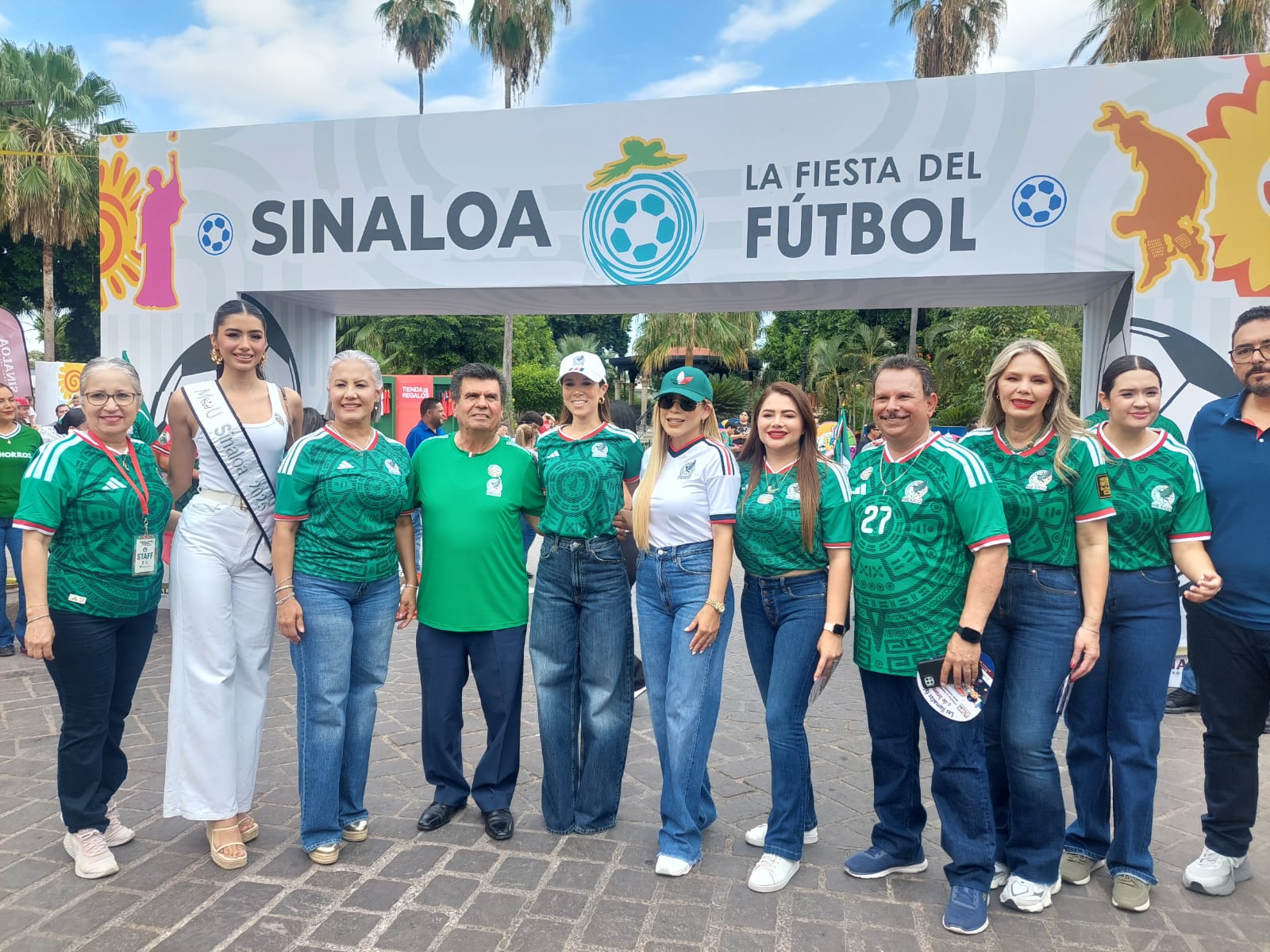Personas con playeras de la selección mexicana y al fondo un templete